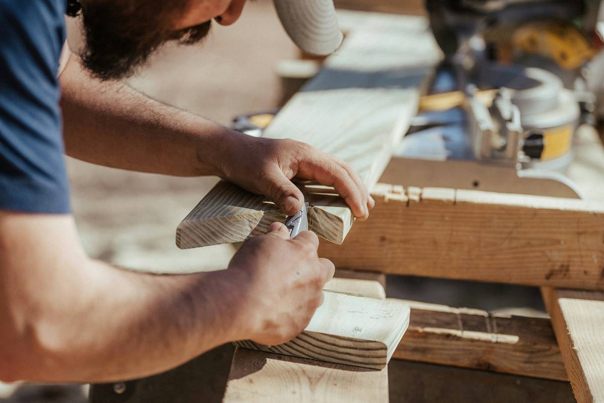 Close-up of hands using a wood router on a wooden board with dust collection visible