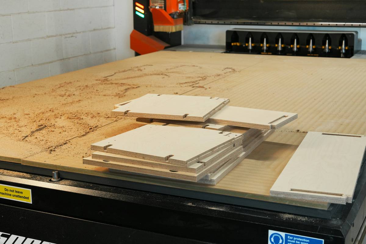 what is a router in woodwork: close-up of a handheld wood router shaping the edge of a pine board with fine dust curling away